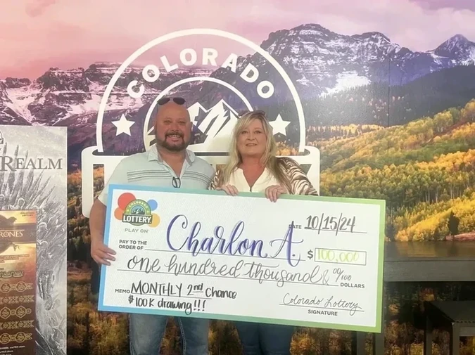 Charlon A. 手持一张 $100,000的巨大支票，背景为科罗拉多州彩票的标志